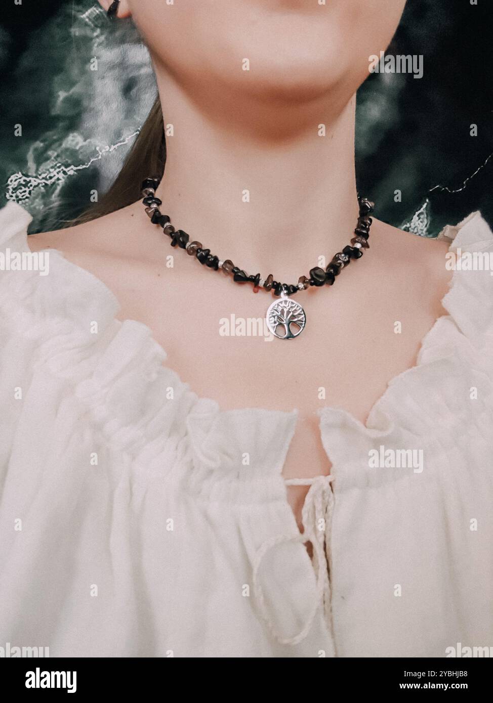 Black obsidian choker with tree of life pendant on woman's neck - Smartphone Captured Stock Image