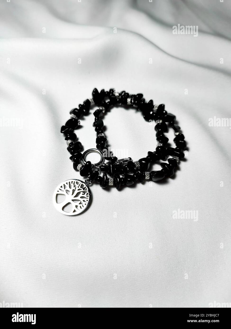 Black agate gemstone necklace with tree of life charm at white background. Female accessory, woman's fashion. Natural stone jewelry flat lay, beaded - Smartphone Captured Stock Image