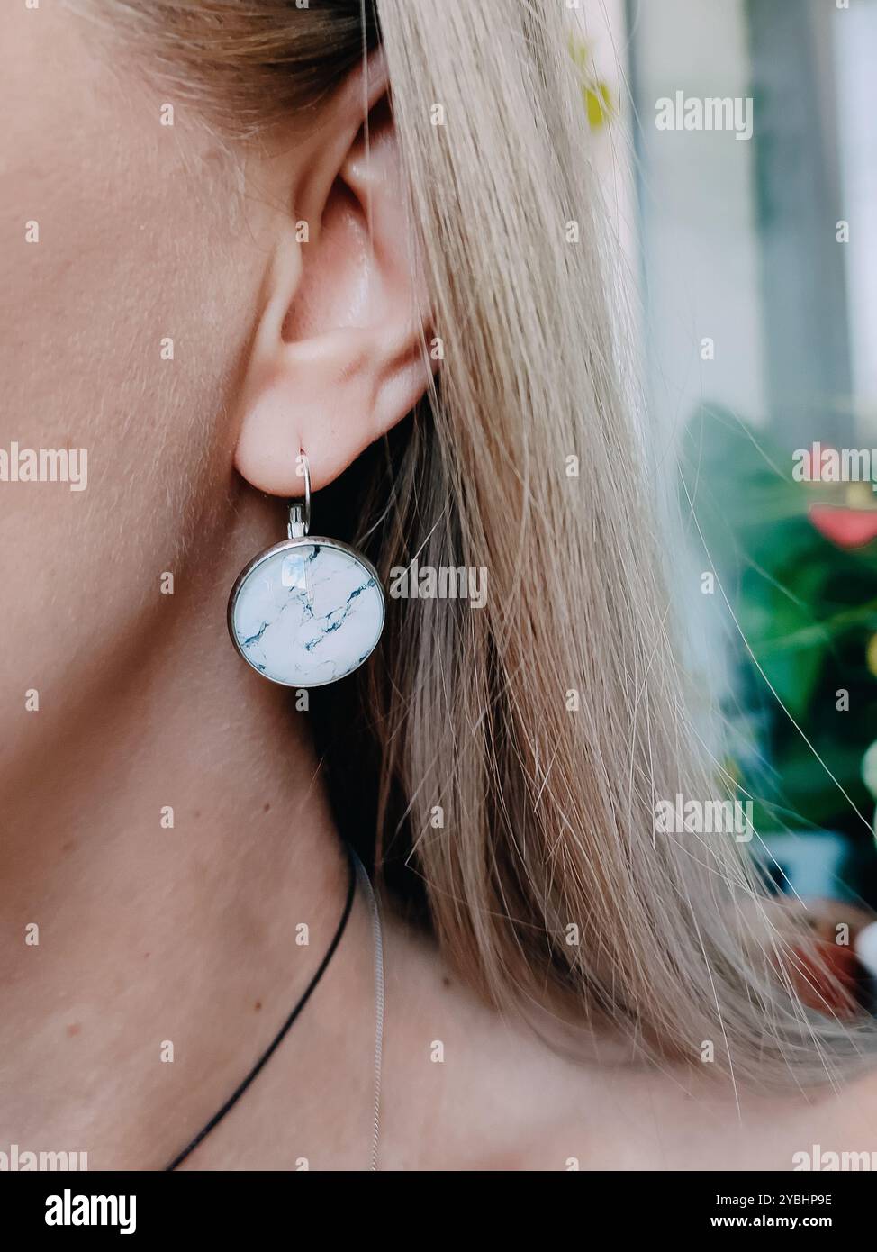 Handmade round white marble resin earrings transparent finish on blonde hair woman's ear. Nature-inspired jewelry collection, jewellery model, stylish - Smartphone Captured Stock Image