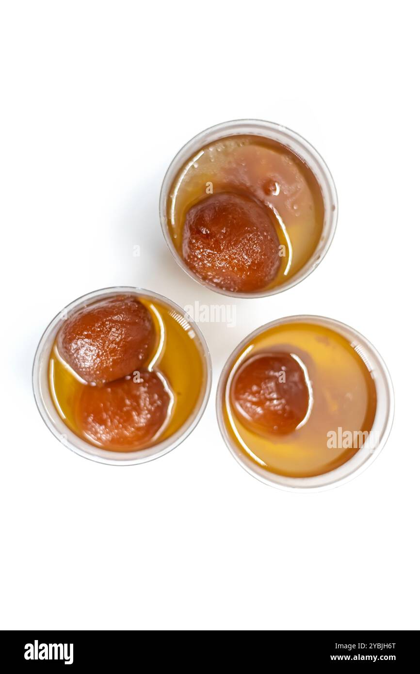 Top view of delicious gulab jamun sweets floating in sugar syrup in small three cups on white background. selective focus Stock Photo