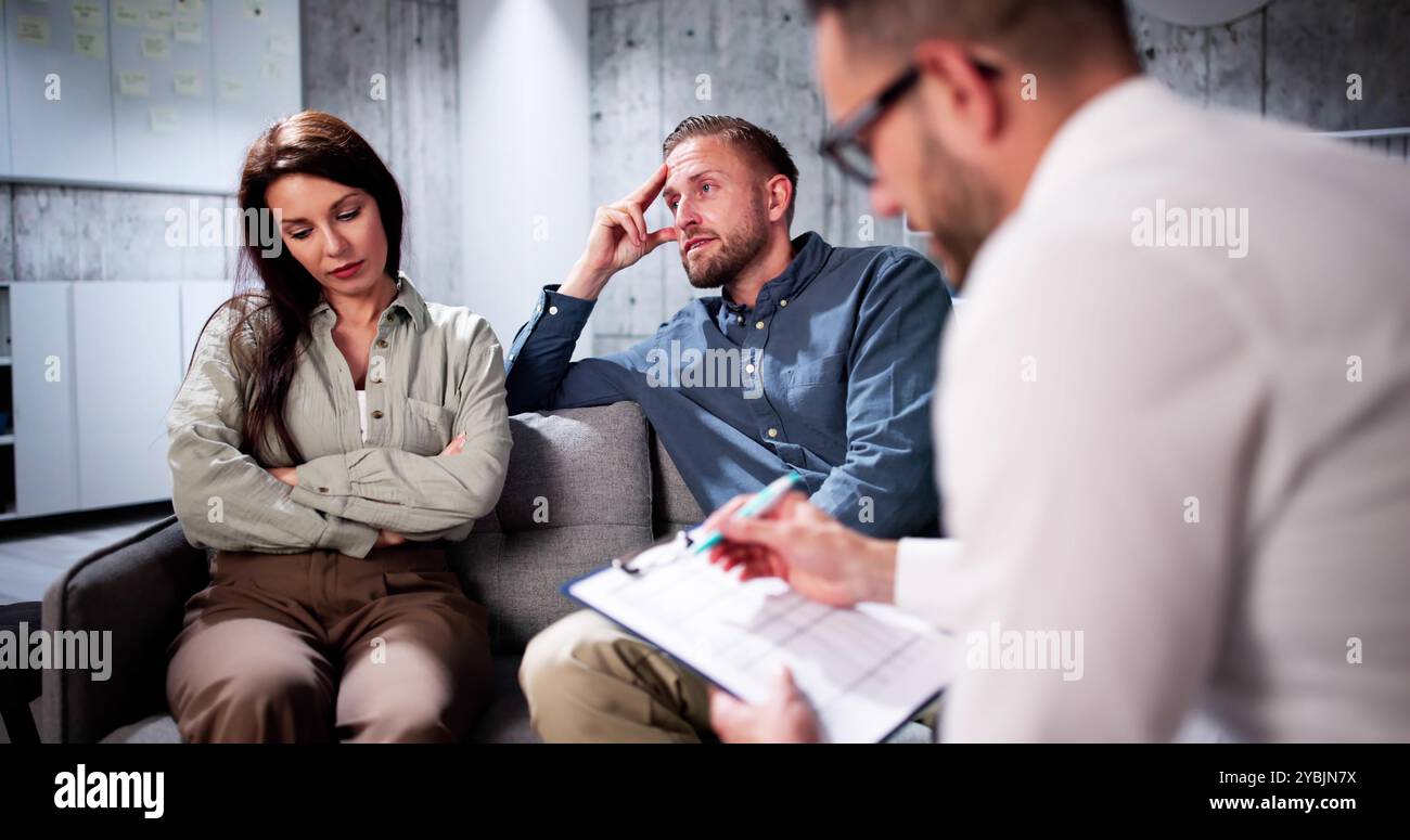Sad Young Couple Sitting On Sofa With Female Psychologist Stock Photo