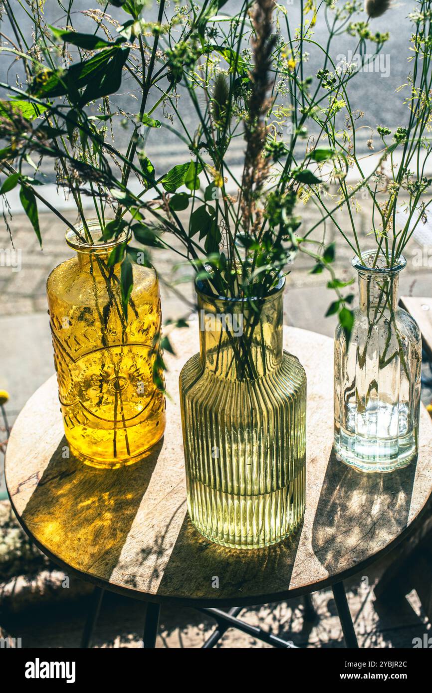 Garden flowers in coloured glass bottles Stock Photo