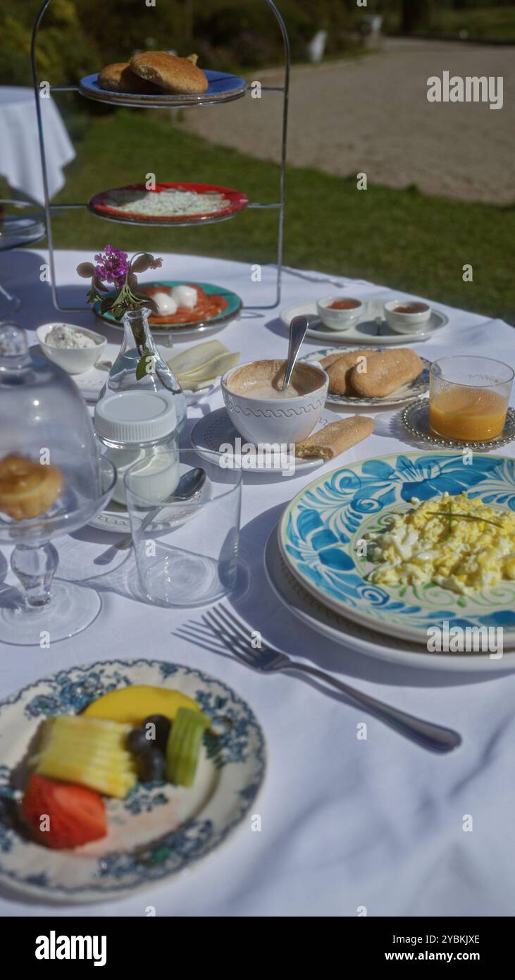 Outdoor breakfast setup with various food items on a white tablecloth ...