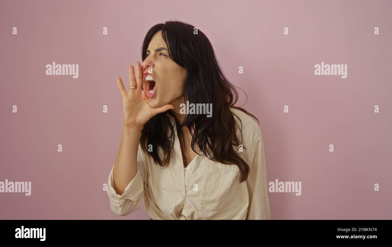 Young hispanic woman shouting against an isolated pink background looks determined and expressive Stock Photo