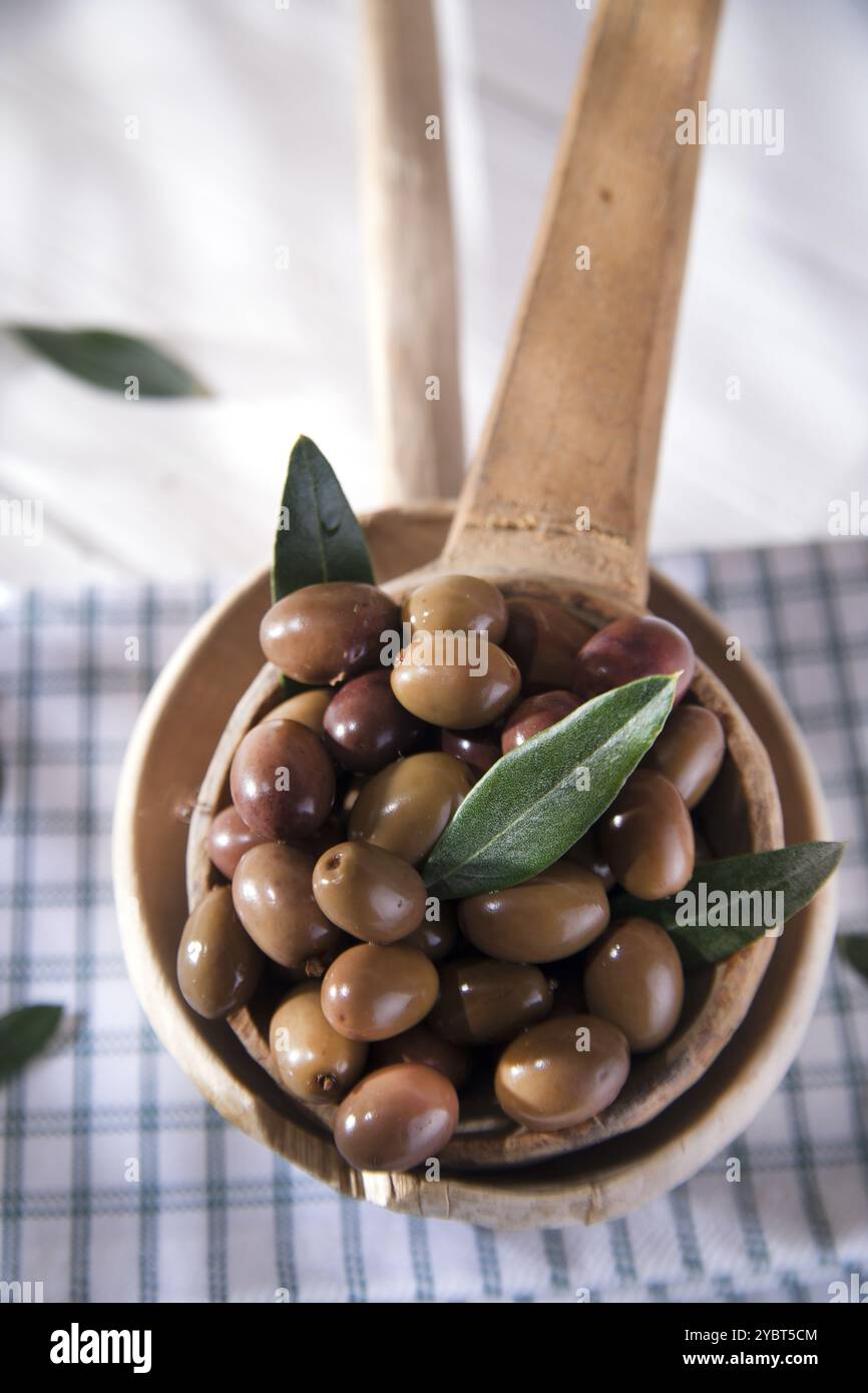 Presentation of a small group of black olives on wooden ladle Stock Photo