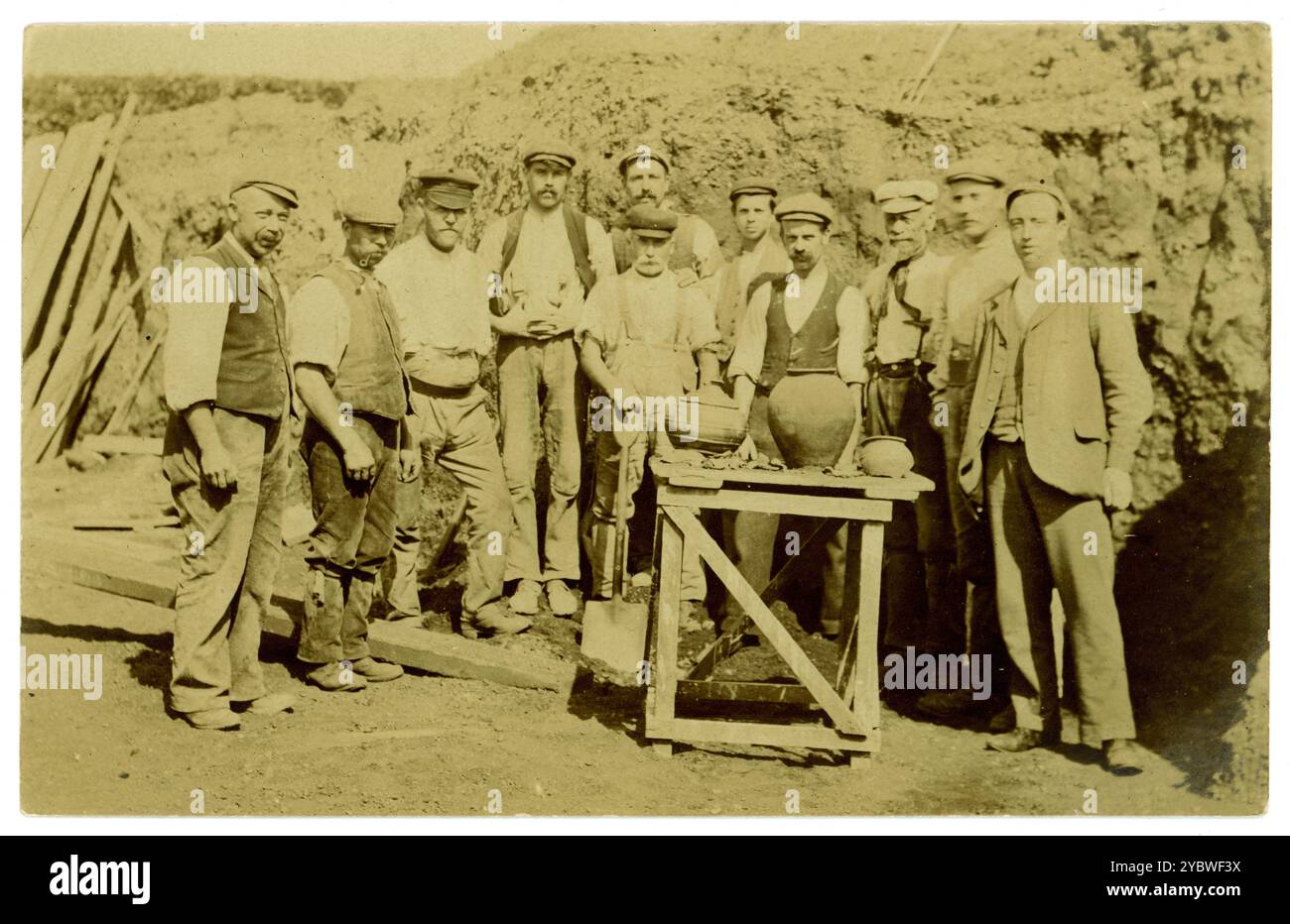Original early 1900's postcard of group of workers perhaps archaeologists too, with a selection of ancient clay pots perhaps unearthed in quarry working, mining, or road construction. Archaelogical dig finds displayed on a table for a photograph. Archaeological excavation. circa 1910, U.K. Stock Photo
