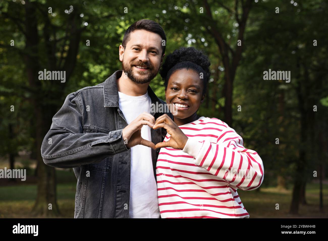 International relationships. Lovely couple making heart with hands outdoors Stock Photo