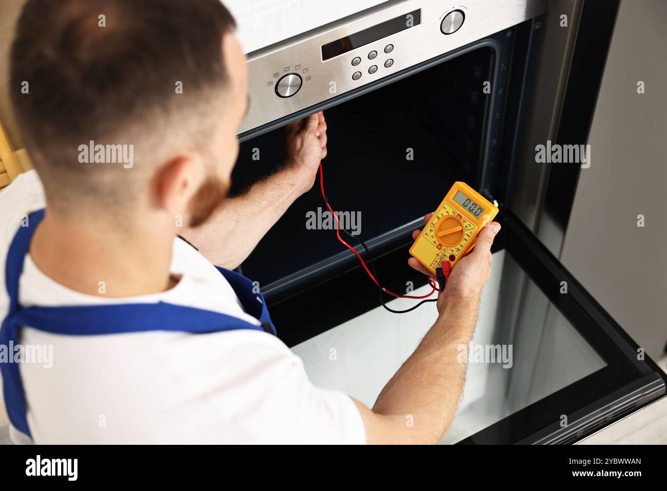 Repairman testing oven element with multimeter, above view Stock Photo