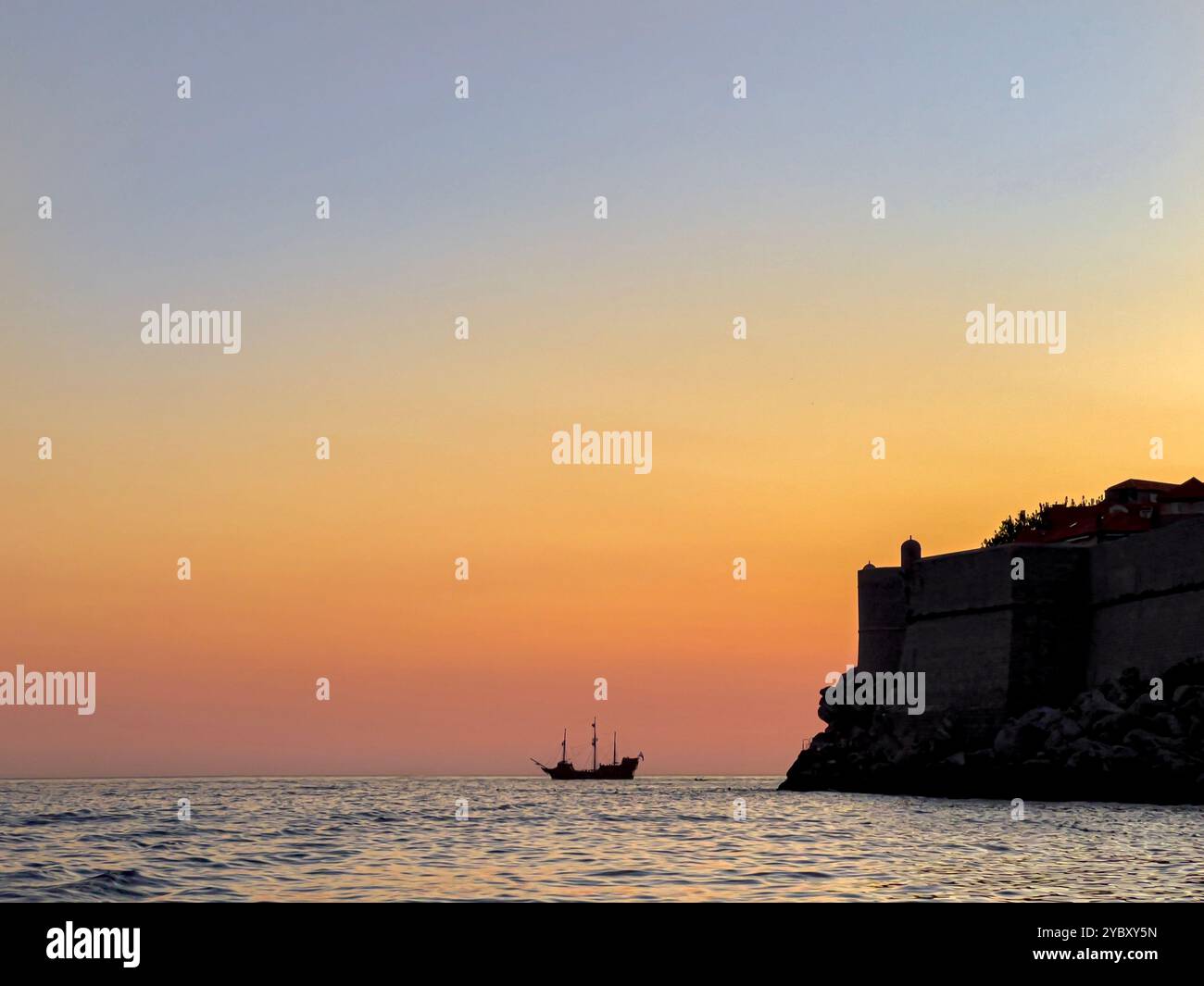 Tourist boat on sunset cruise silhouetted against the evening sky and city walls of Dubrovnik, Croatia - Smartphone Captured Stock Image