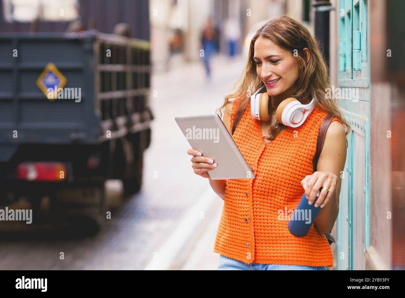 Latin woman holding reusable water bottle while using digital tablet Stock Photo