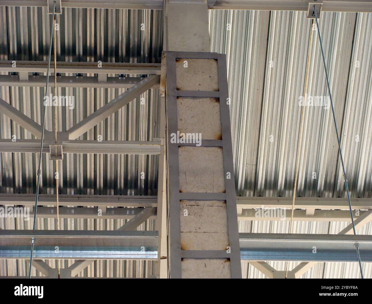 Close-up of concrete column with metal reinforcements supporting industrial building structure. Stock Photo