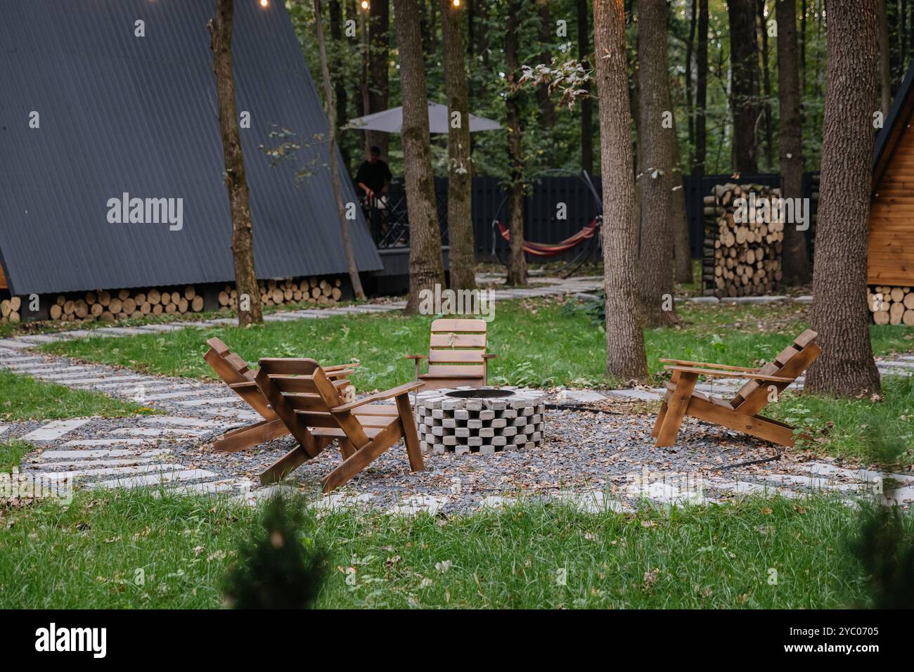 Cozy fire pit seating area in forest glamping with glowing string ...