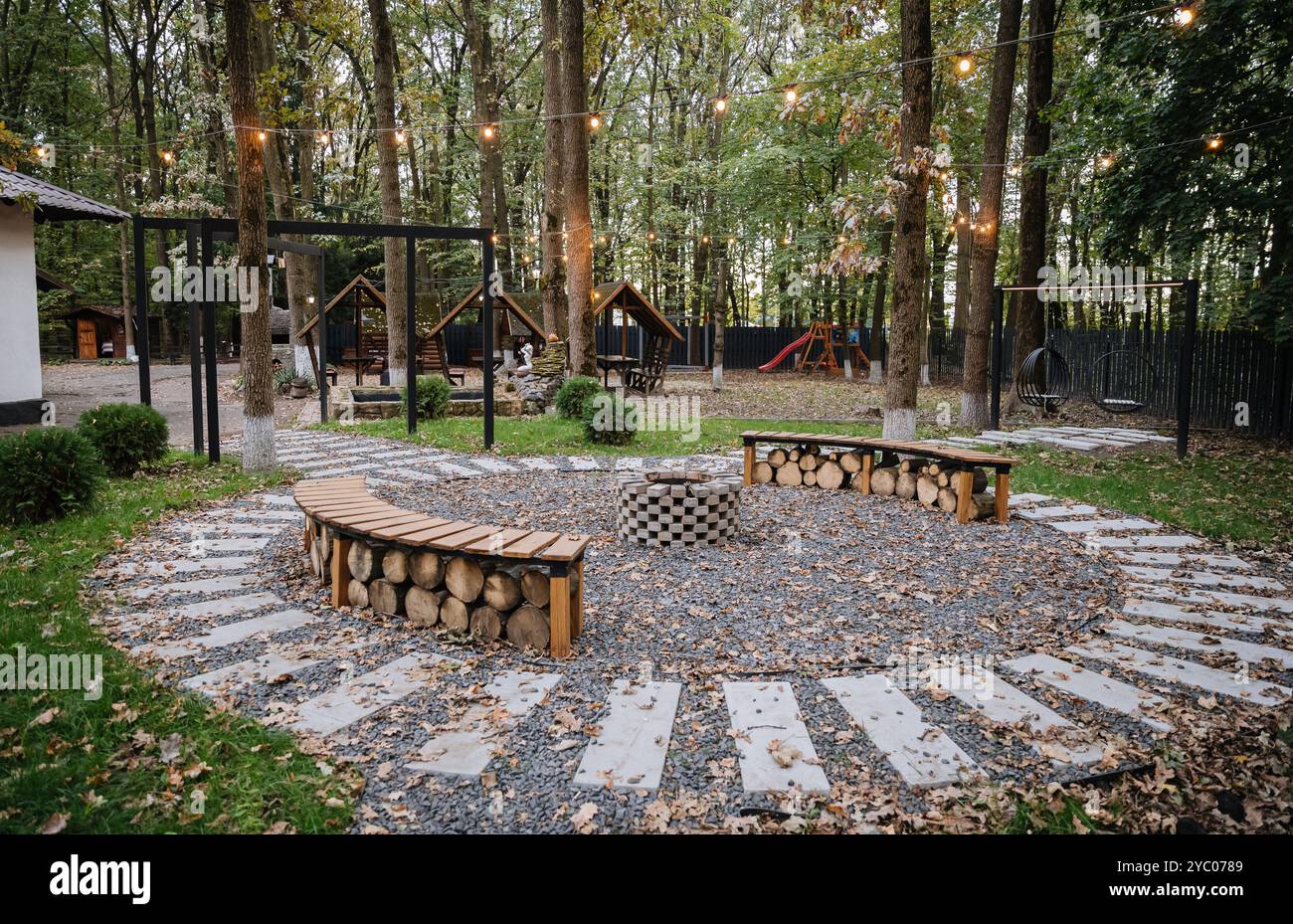 Cozy fire pit seating area in forest glamping with glowing string ...