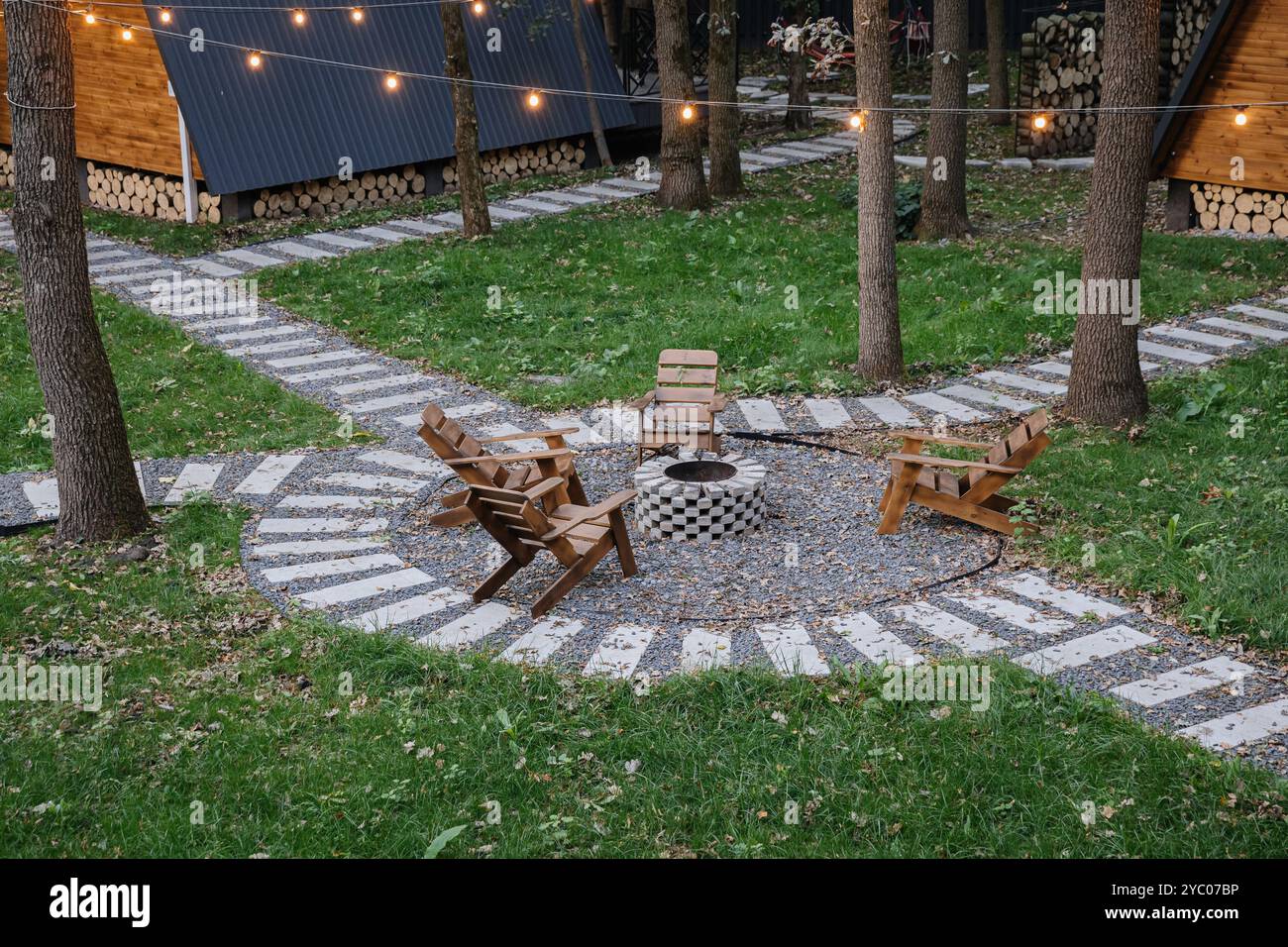 Cozy fire pit seating area in forest glamping with glowing string ...