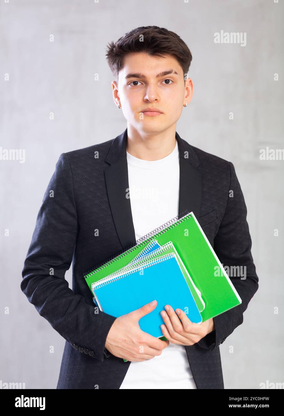 Focused young guy holding stack of notebooks Stock Photo - Alamy