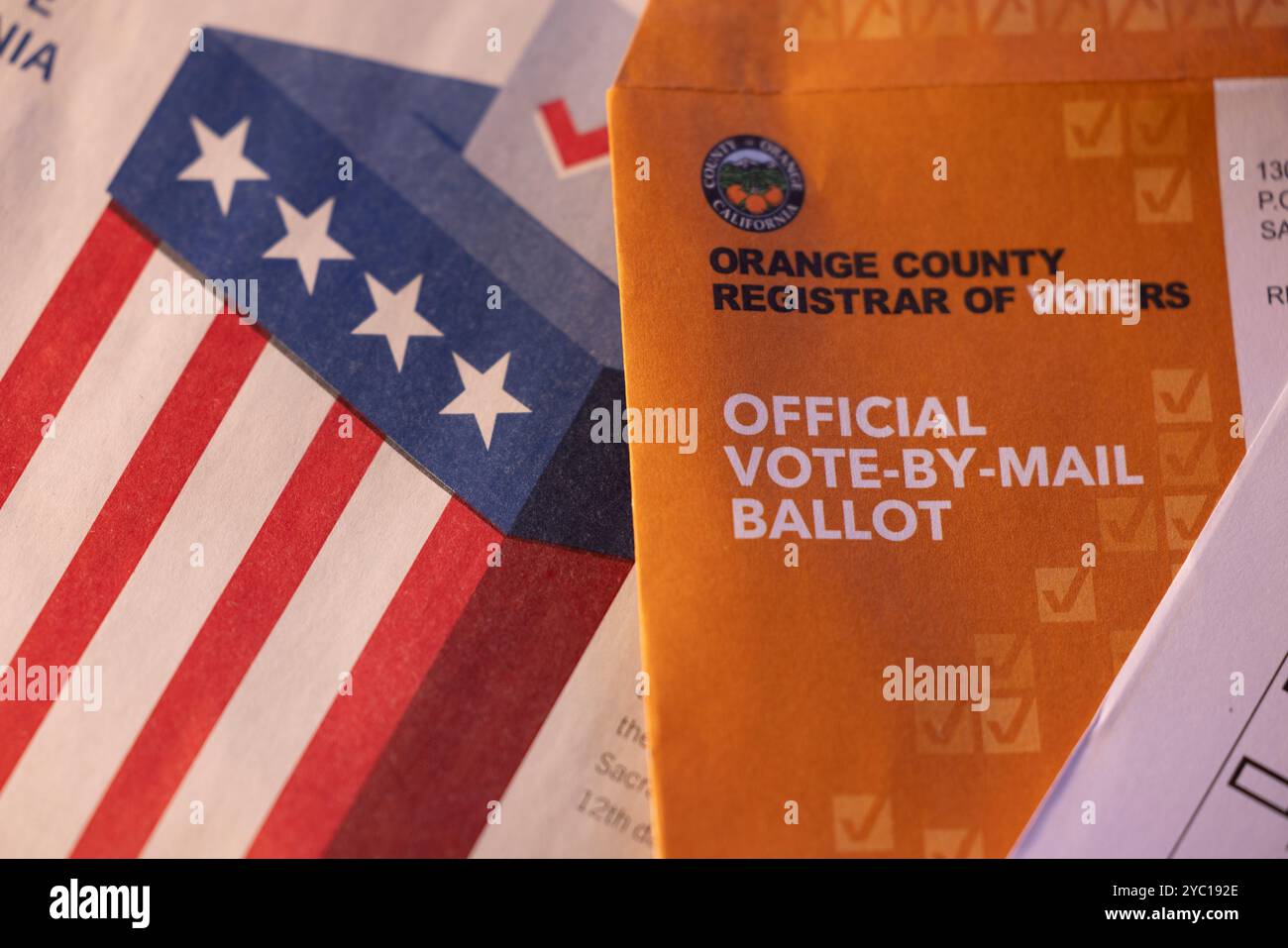 Fullerton, California, USA - October 20, 2024: Afternoon light shines on table of election materials and a vote by mail ballot. Stock Photo