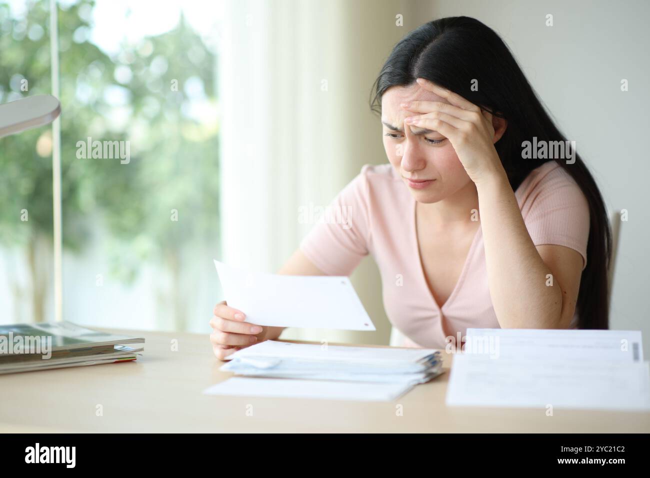 Worried asian woman complaining checking invoice sitting at home Stock Photo