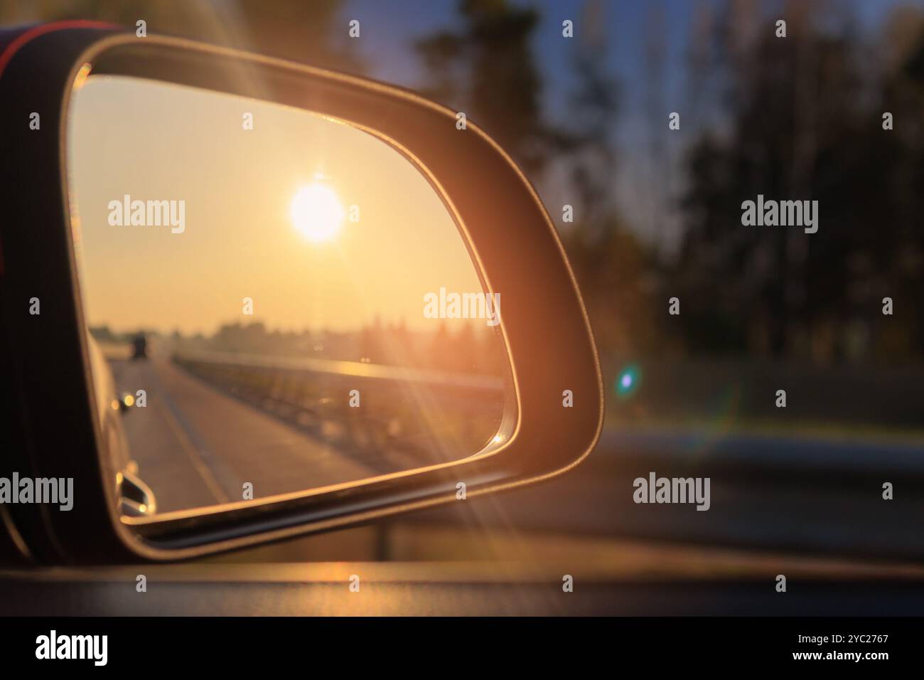 The sun is reflected in the mirror, evening road. View in the side rear ...