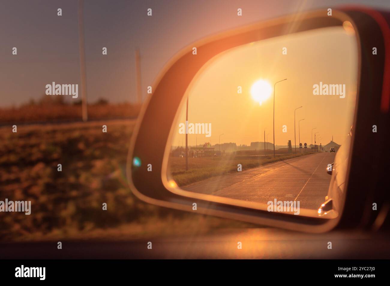 The sun is reflected in the mirror, evening road. View in the side rear ...