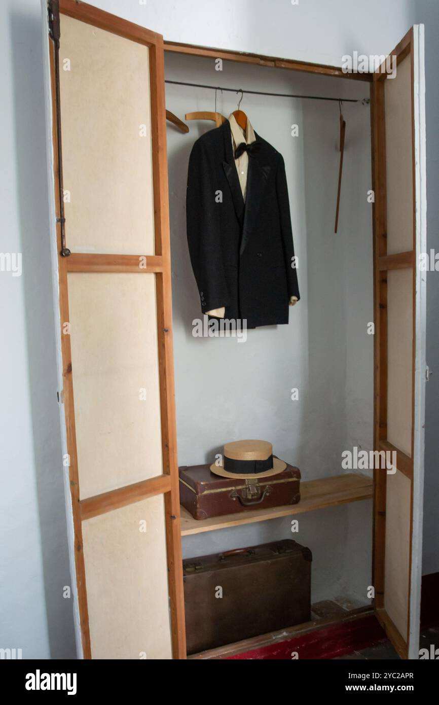 antique built-in wardrobe with a suit hanging with a bow tie, suitcases, and a straw hat belonging to Federico Garcia Lorca in his house in Fuente Vaq Stock Photo