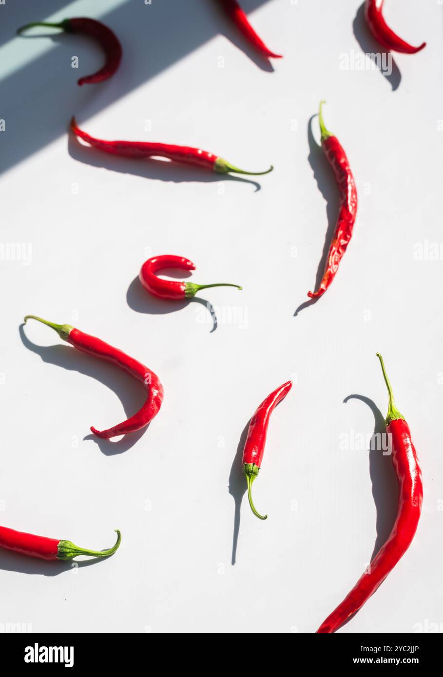 Scattered fresh red chilies on a white background. Stock Photo