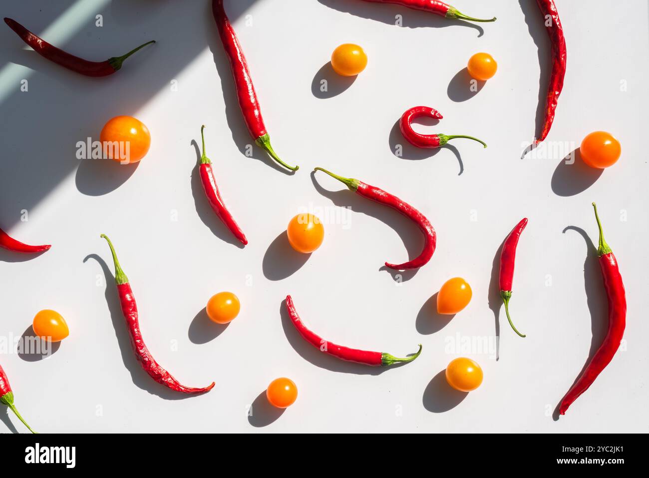 Red chilies and yellow tomatoes scattered on a white background Stock Photo