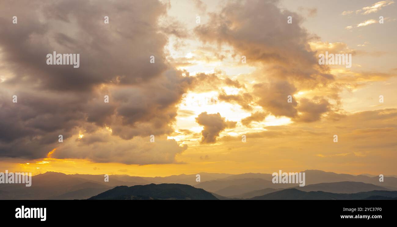 Nature landscape at sunrise with orange sky and soft clouds over peaceful mountain range. Tranquil morning scene. Beauty of dawn and serenity Stock Photo