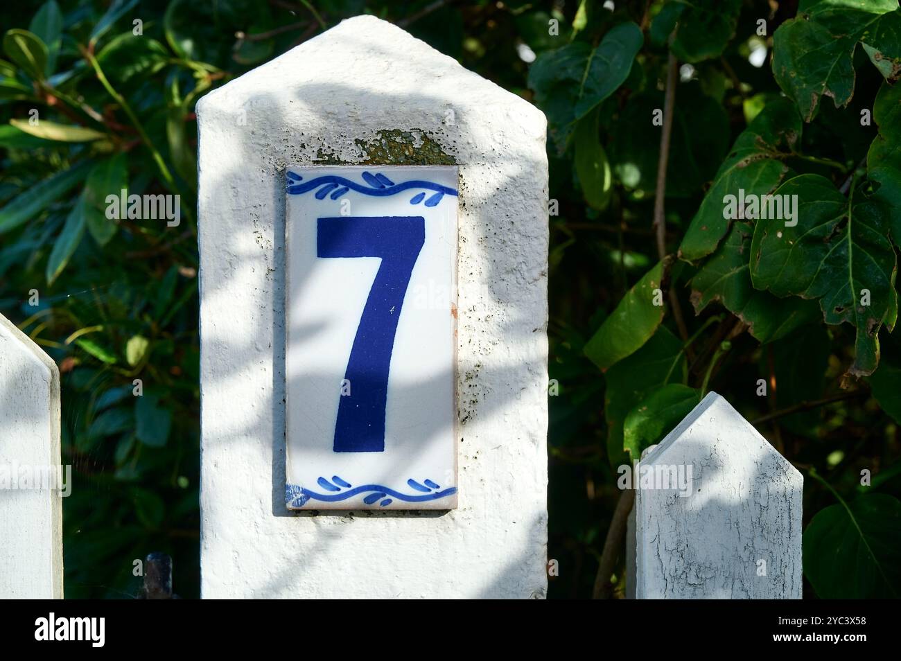 Blue number seven attached to garden gate Stock Photo
