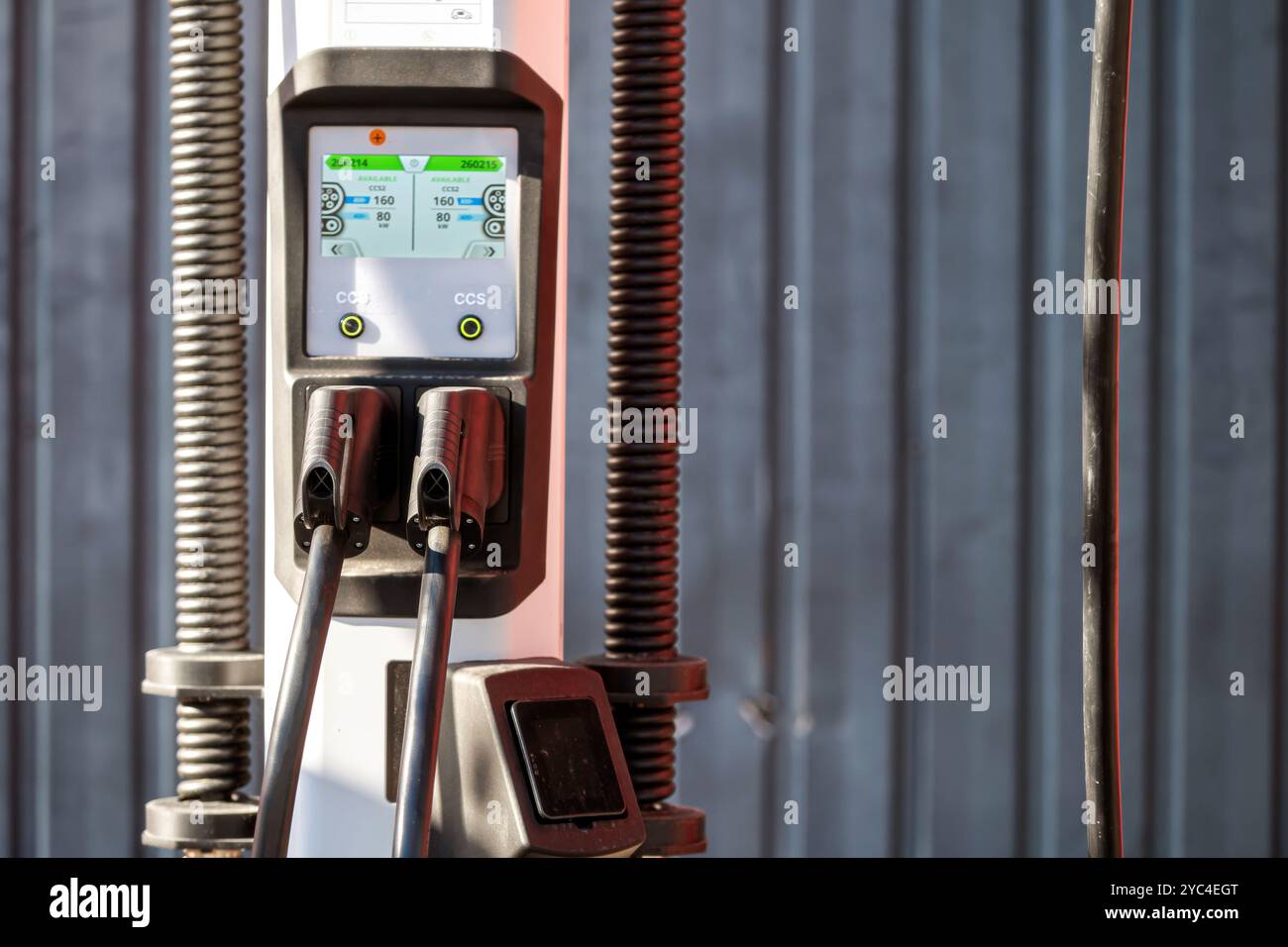 An electric vehicle charger displays charging options and settings during the day. Stock Photo