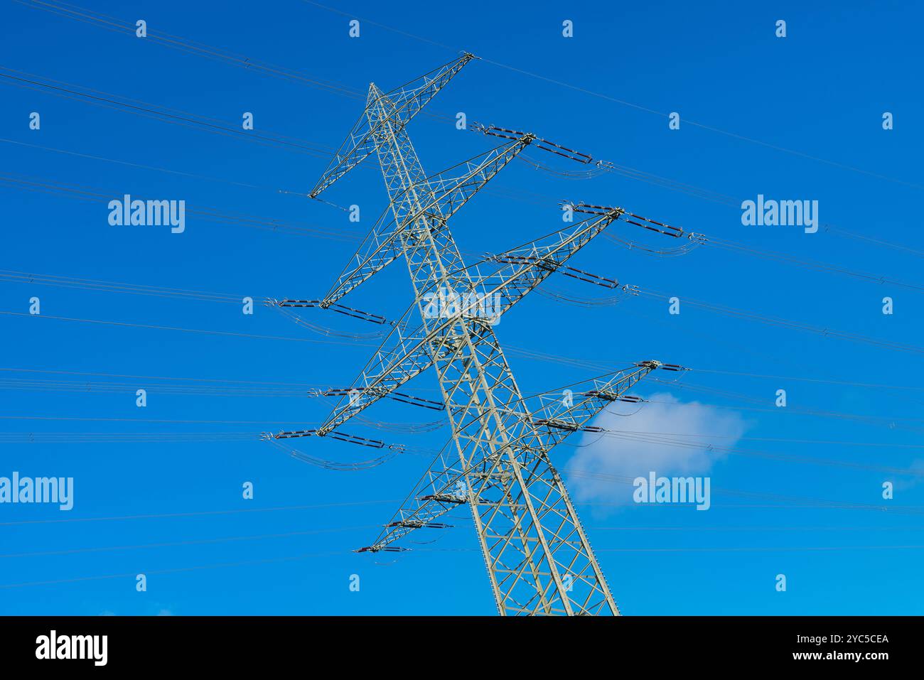 A high voltage power transmission tower stands prominently against a ...