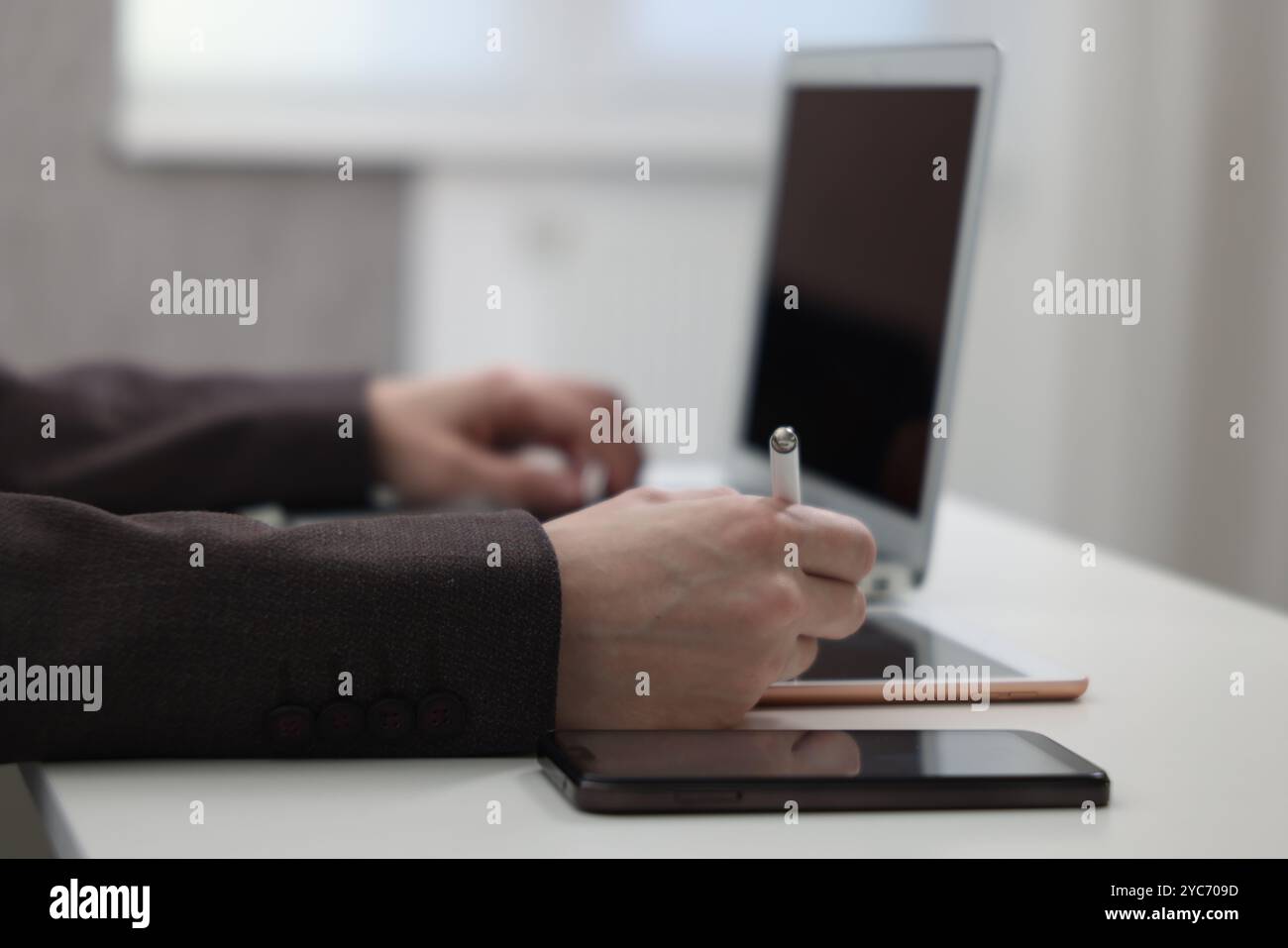 Businessman using different devices at white table indoors, closeup. Modern technology Stock Photo