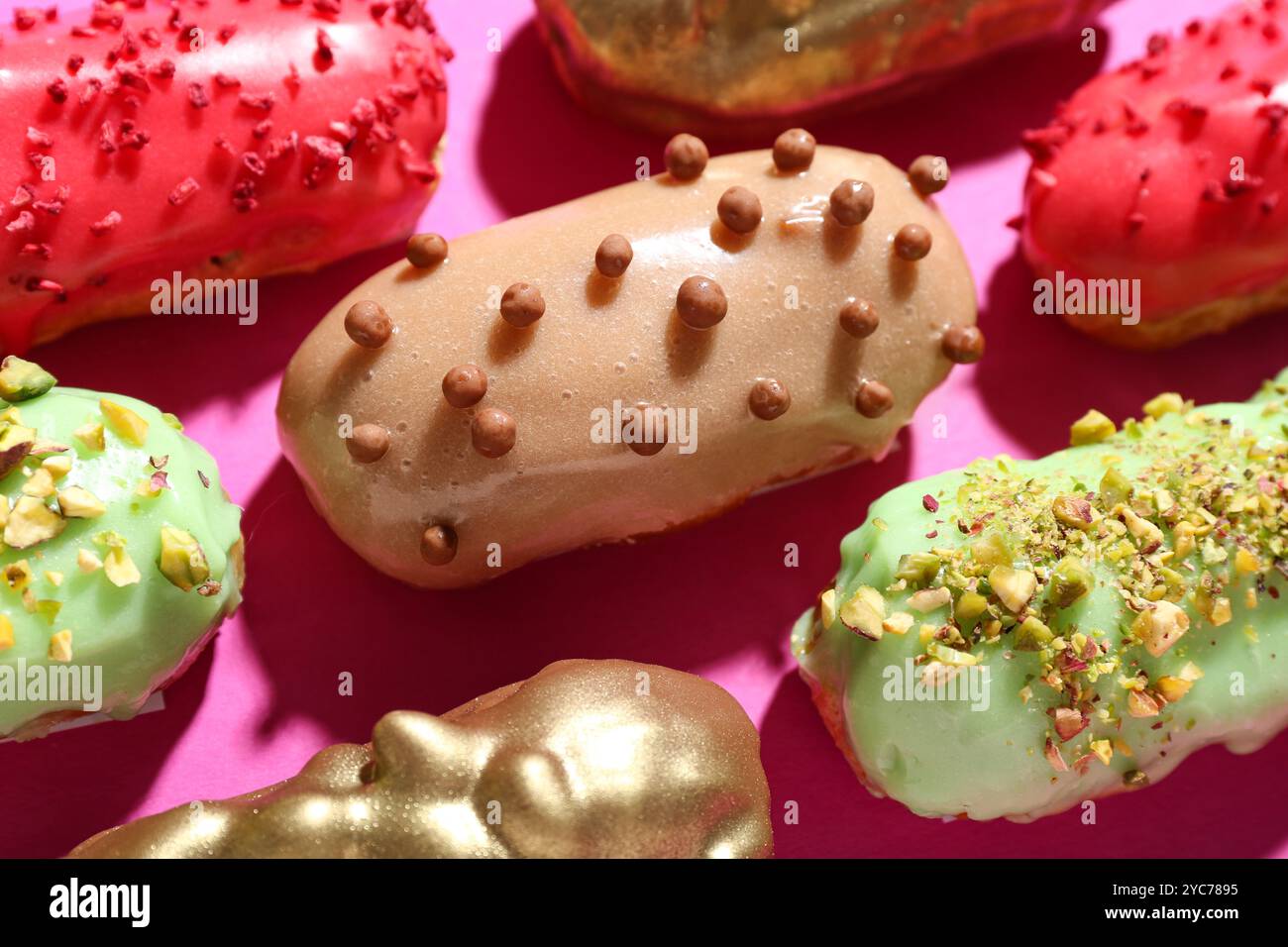 Composition with tasty glazed eclairs on pink background, closeup Stock Photo