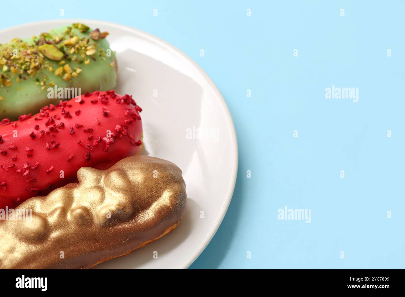 Plate with tasty glazed eclairs on color background Stock Photo