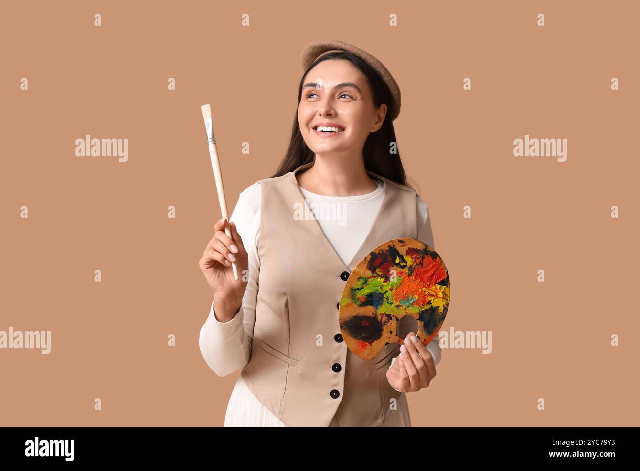 Beautiful female artist with brush and palette on beige background ...