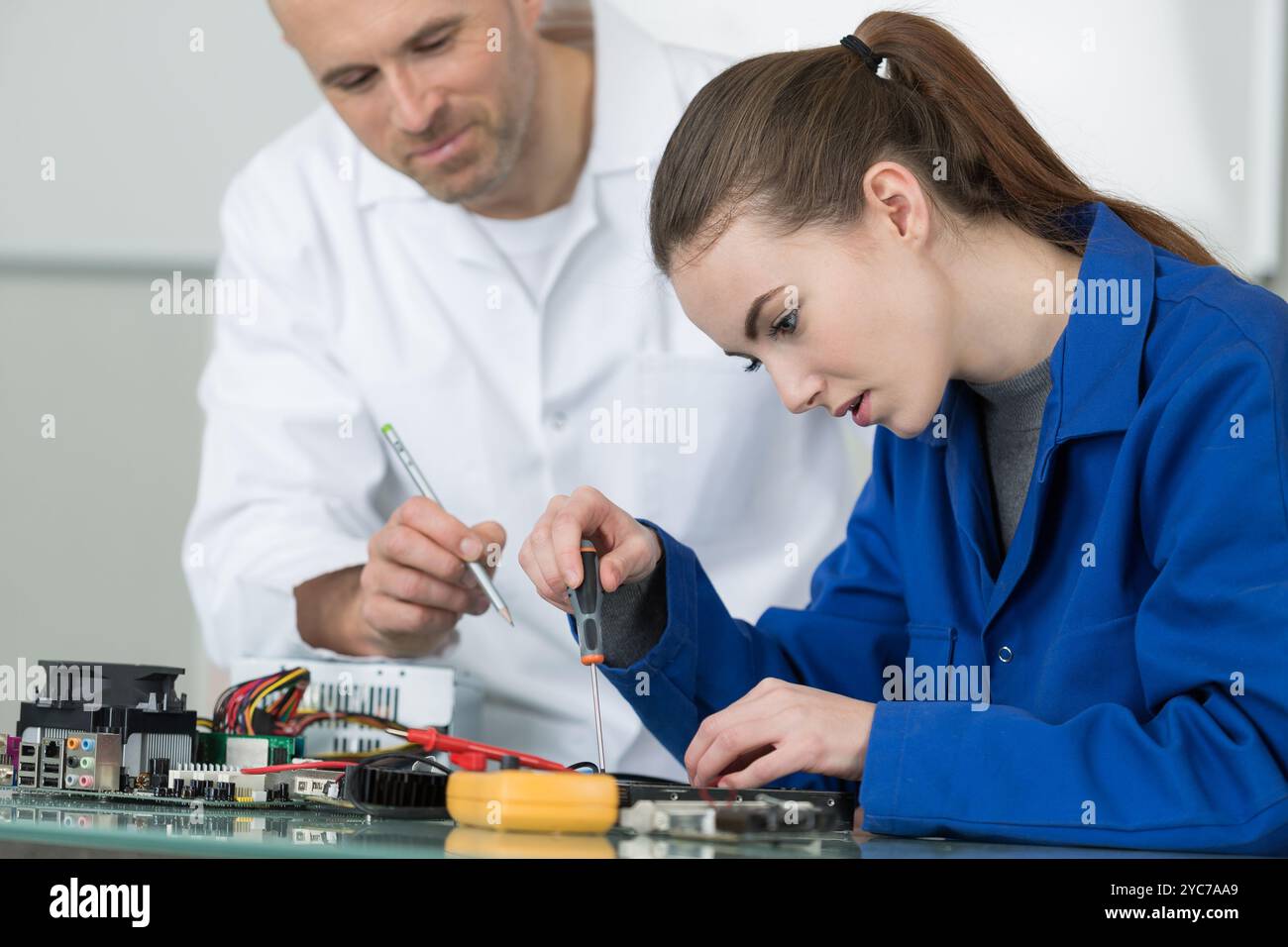 supervisor watching over electronics students at work Stock Photo