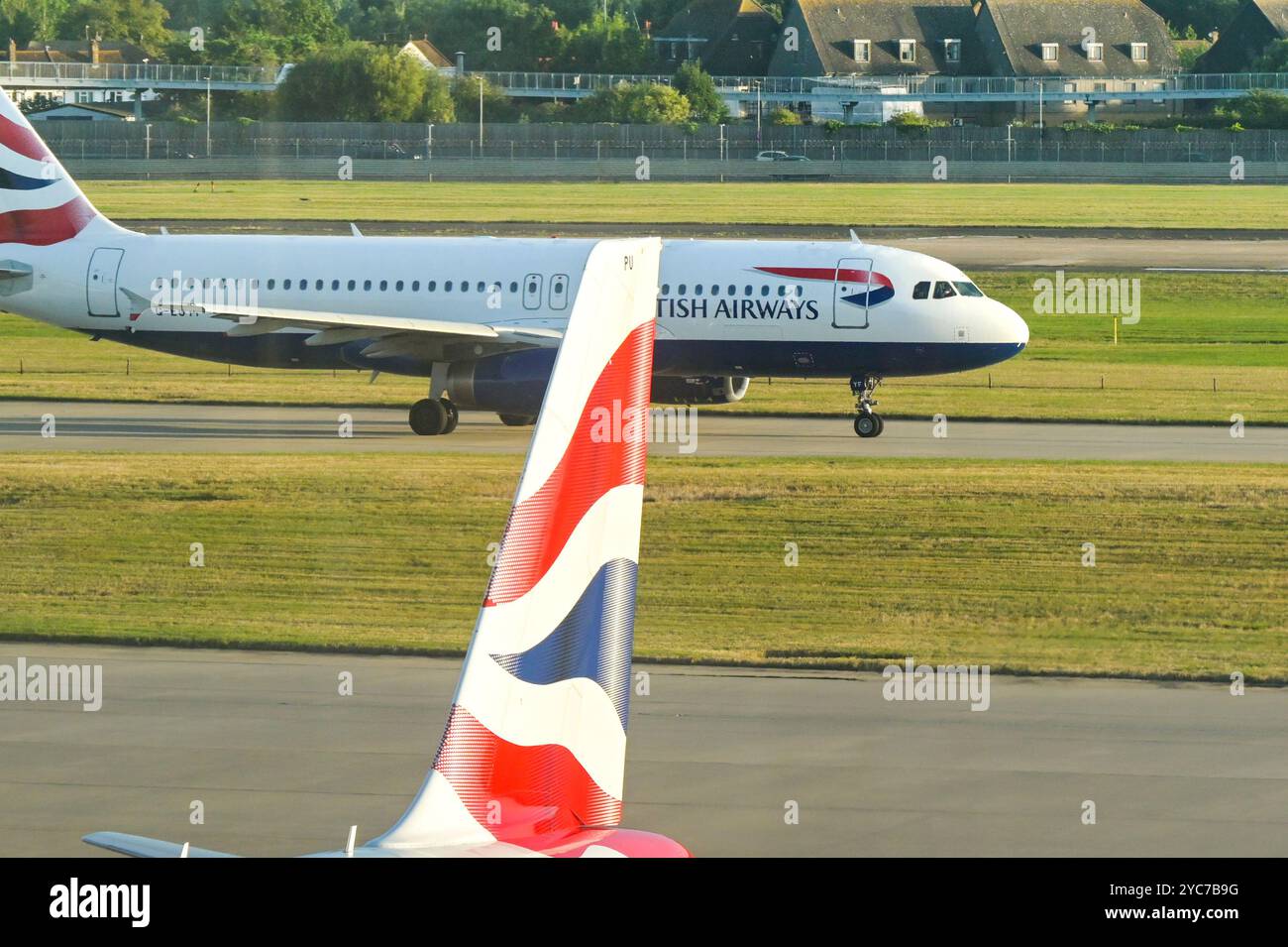 London, England, UK - 21 August 2024: British Airways Airbus A320 jet (registration G-EUYF) taxiing past the tail of another of the airline's aircraft Stock Photo