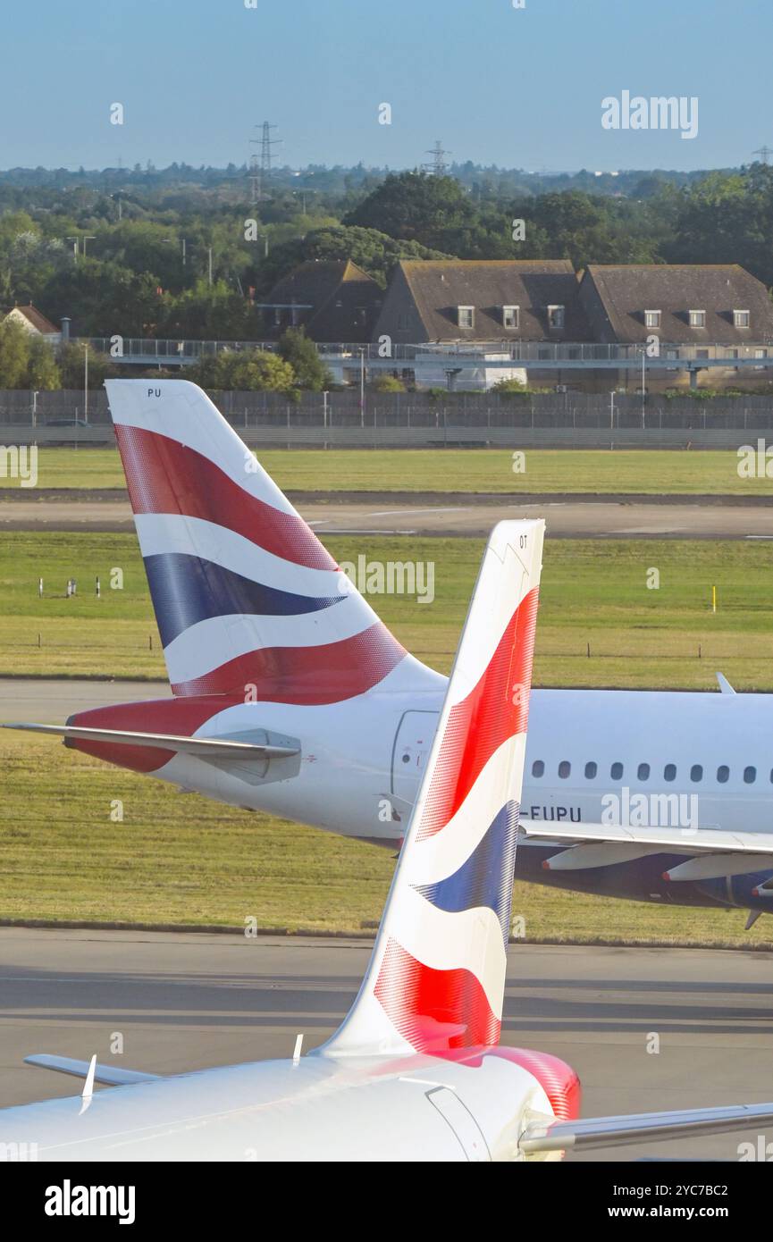 London, England, UK - 21 August 2024: British Airways Airbus A319 jet passing the tail of another of the company's aircraft at London Heathrow airport Stock Photo