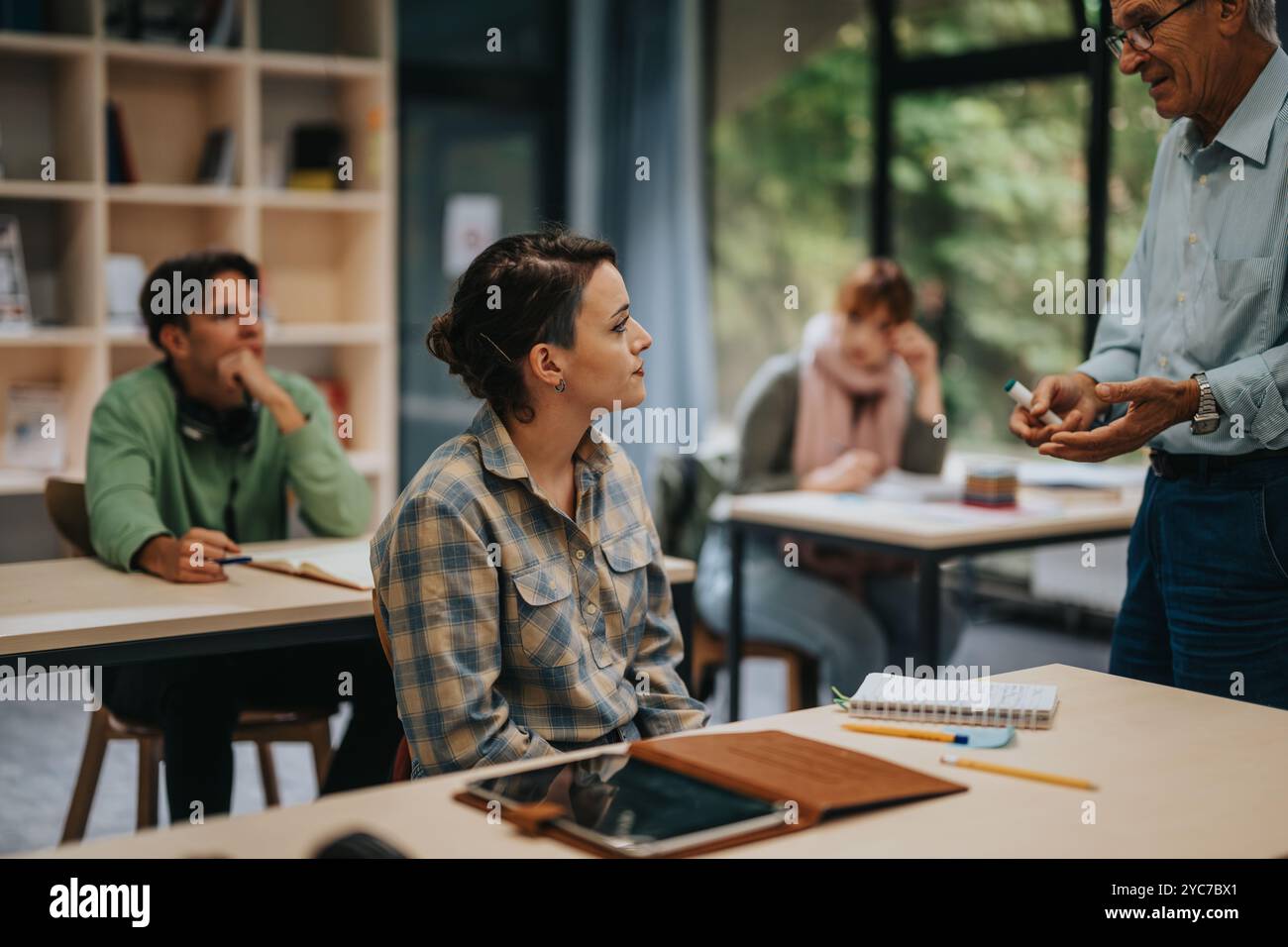 Students engaged in classroom discussion with elderly professor Stock Photo