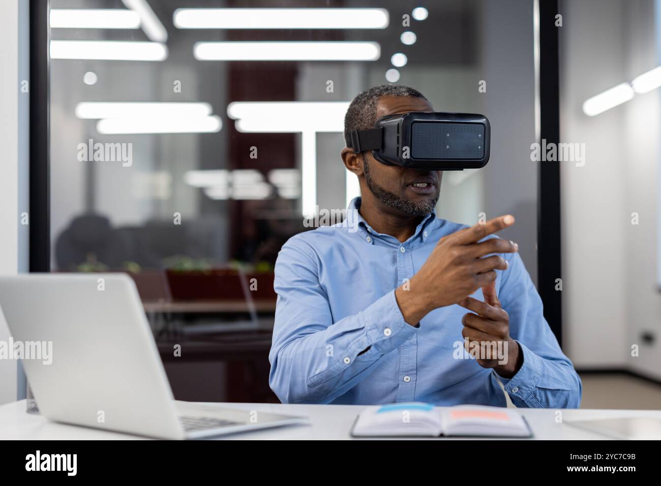 African American mature businessman in office using virtual reality headset for demonstration. Innovating with technology in corporate setting, enhanc Stock Photo
