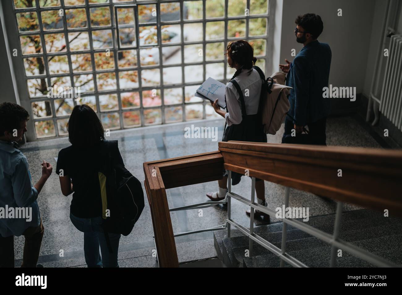 Students discussing study plans while walking down the stairs Stock Photo