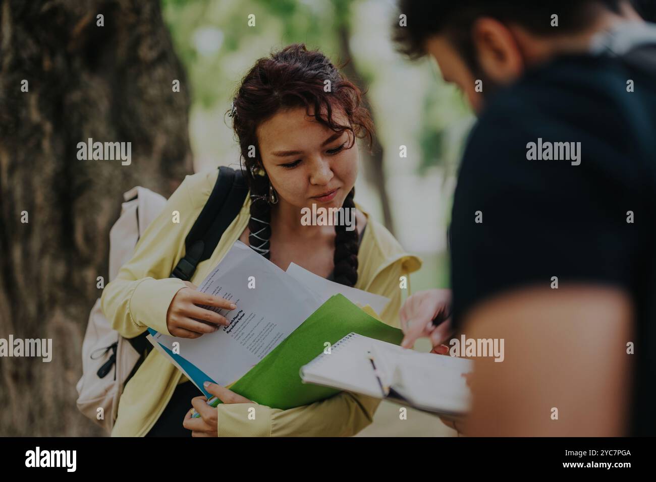 Multicultural students collaborating on schoolwork in a park setting outdoors Stock Photo