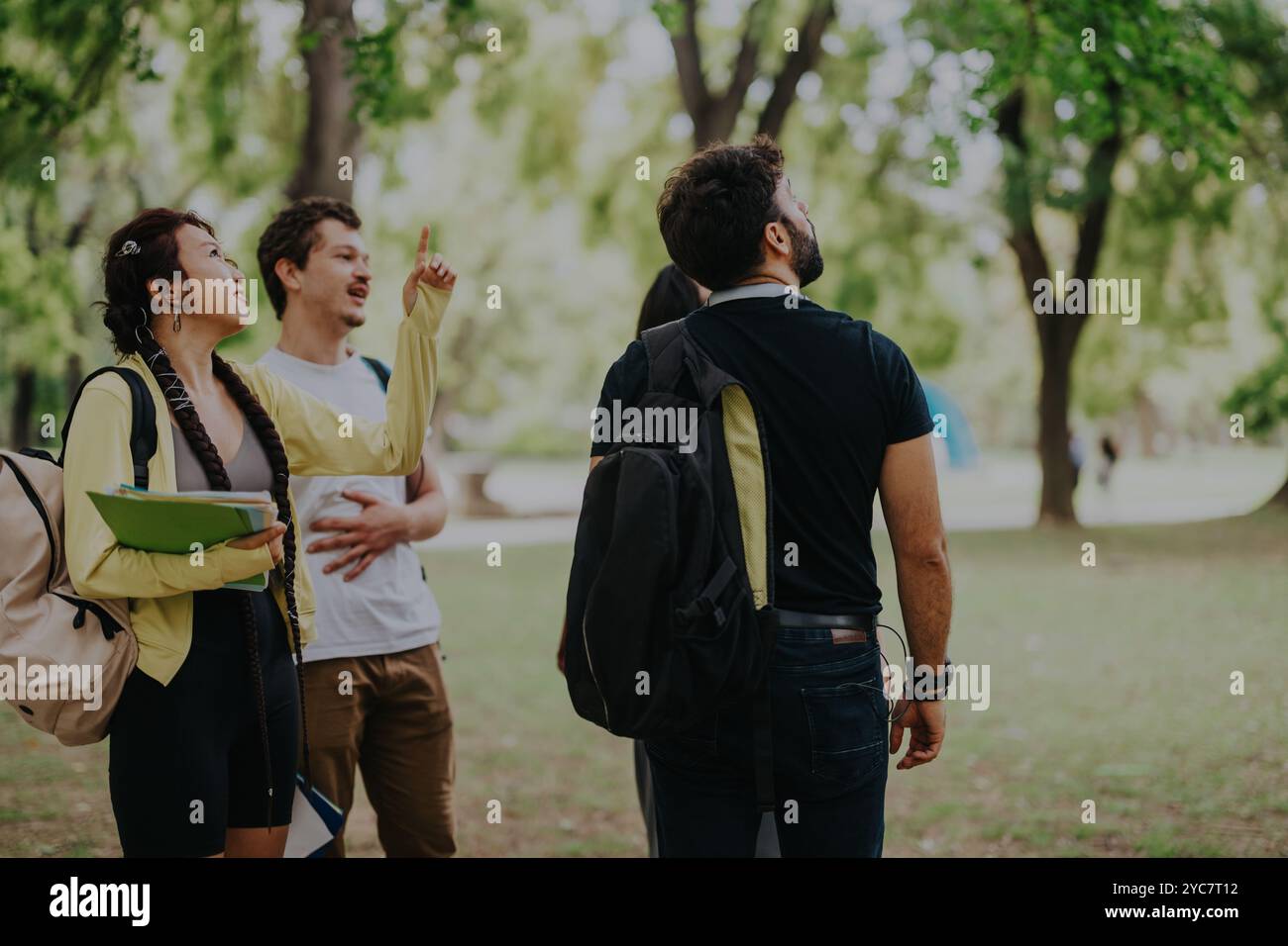 Multicultural students collaborating outdoors on school projects in a park setting Stock Photo