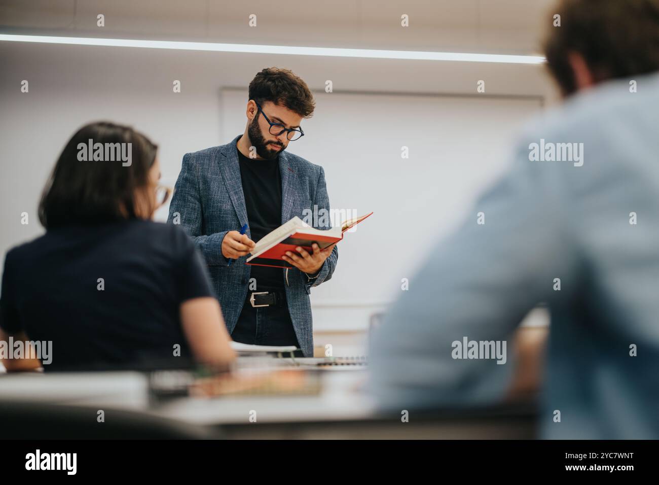 Professor assisting students in a classroom setting during a lesson Stock Photo