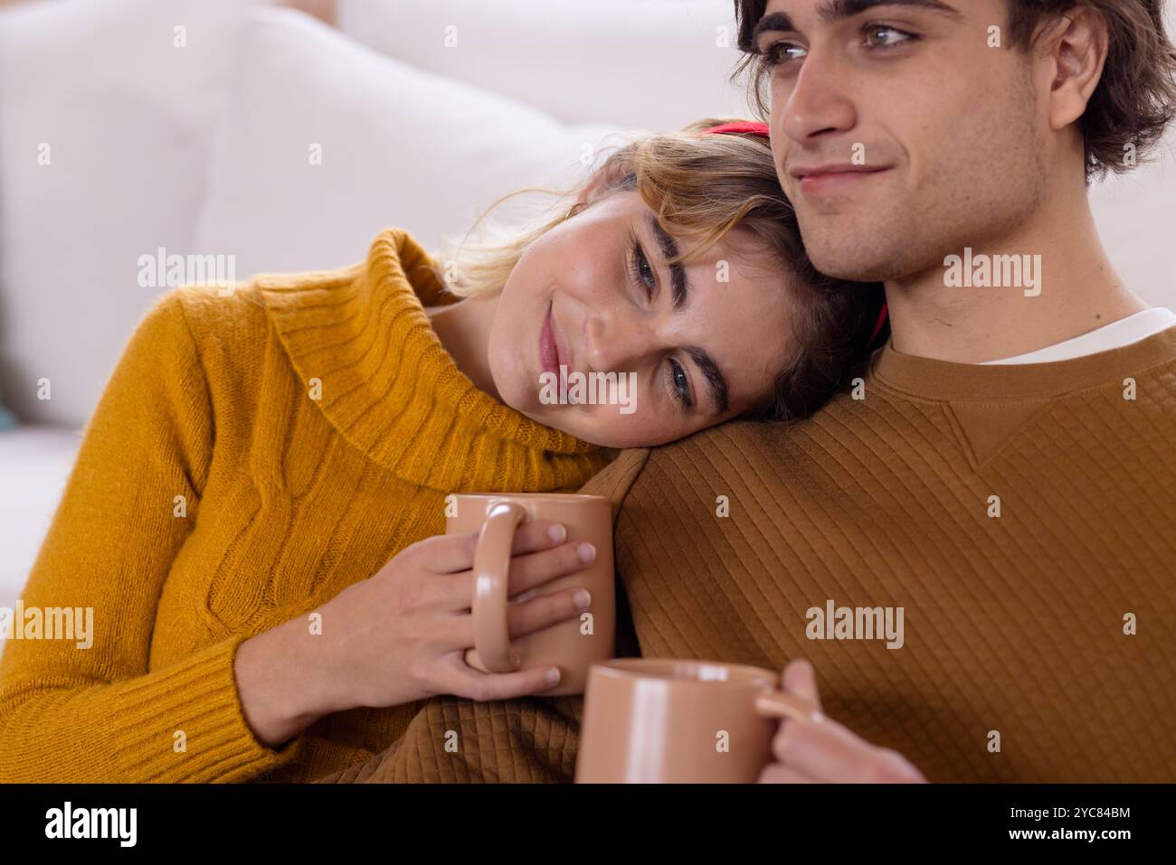 Cozy couple enjoying hot drinks, relaxing together at home during ...