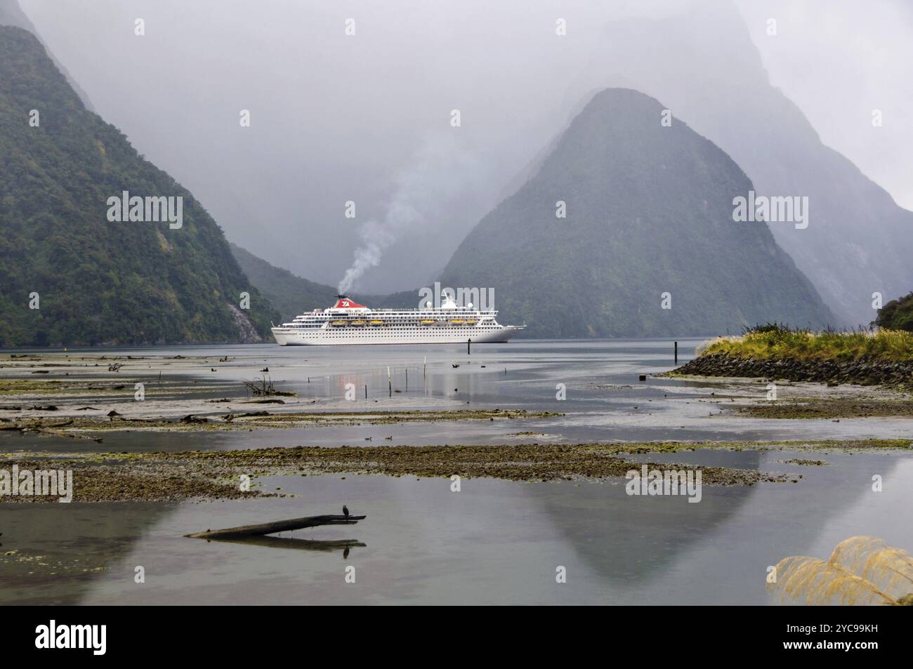 Cruise ship in the evening of an overcast day in the majestic Milford Sound on the South Island of New Zealand Stock Photo