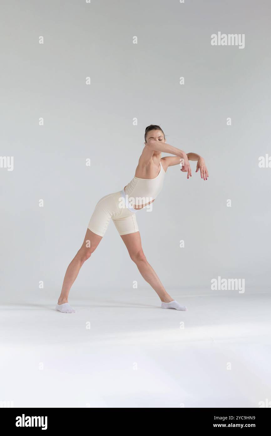 Female dancer in a beige outfit, holding a perfect backbend with one ...