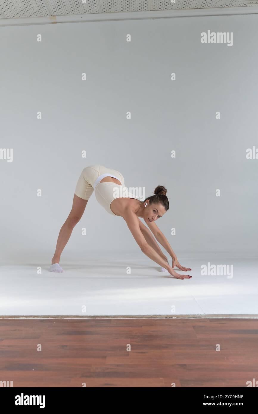 Female dancer in a beige outfit, holding a perfect backbend with one ...