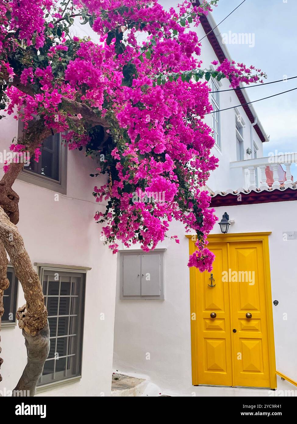 Romantic building with pink flowers and yellow door in Greece, Hydra. - Smartphone Captured Stock Image