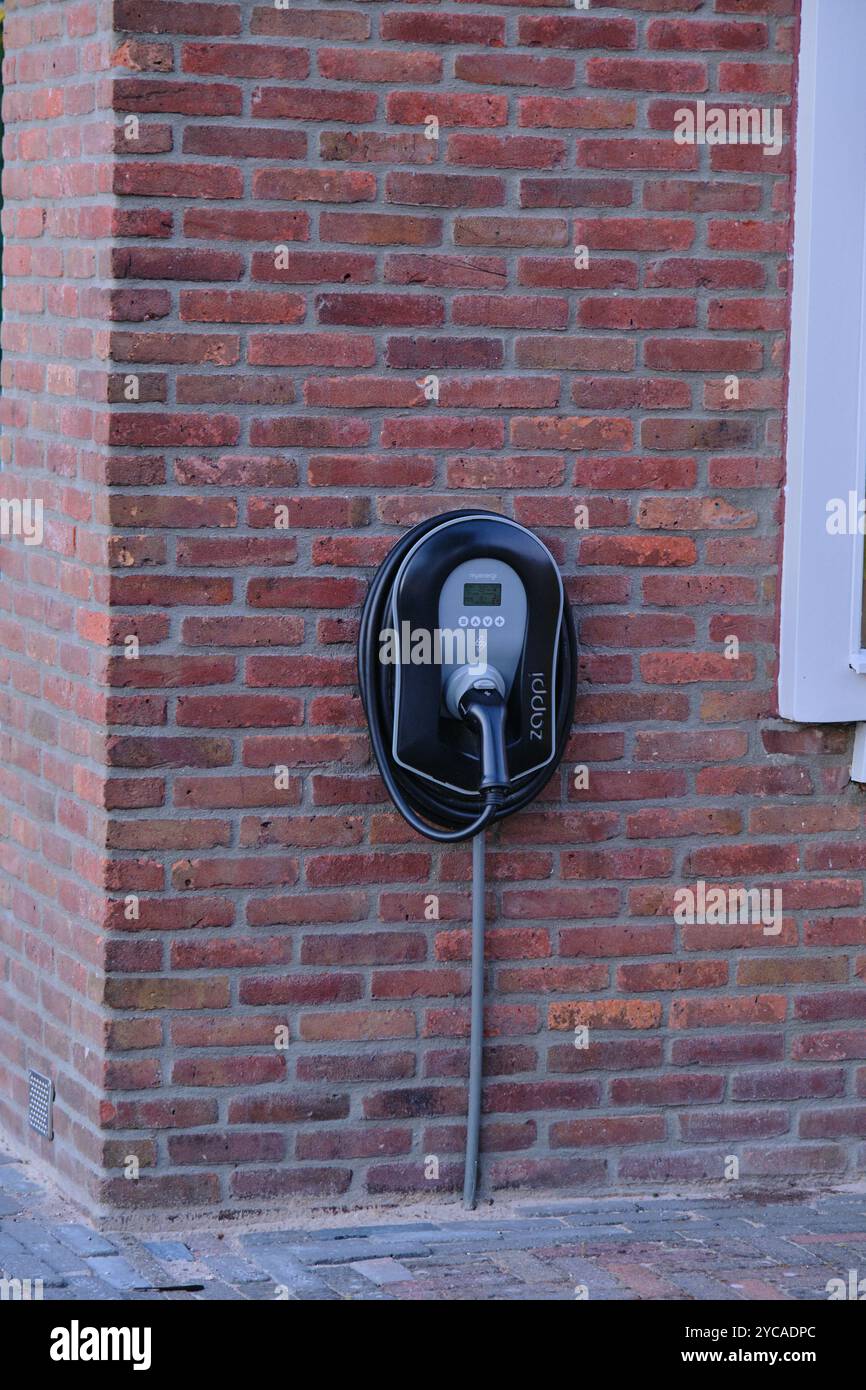an electric vehicle charger mounted on a red brick wall, symbolizing sustainable energy solutions and the growing trend of electric vehicle infrastruc Stock Photo