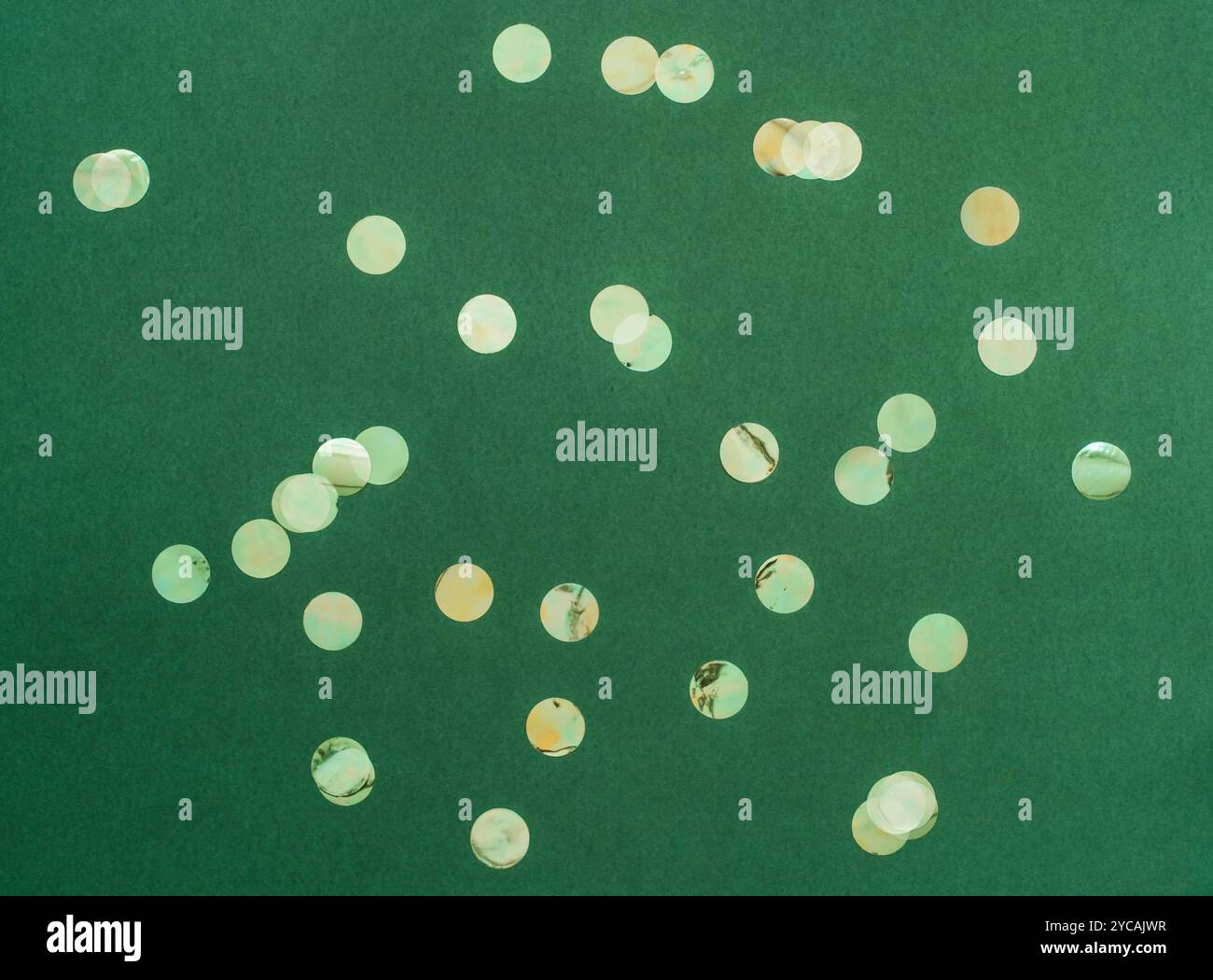 Festive flat-lay arrangement featuring green glittery baubles scattered across green background. Top view. Copy space. Minimal Christmas or New year b Stock Photo